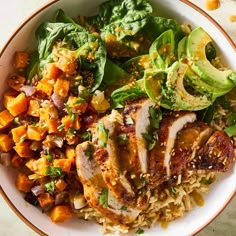 a white bowl filled with rice, meat and veggies on top of a table