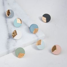 four pairs of gold, silver and blue studs on a marble surface with white background