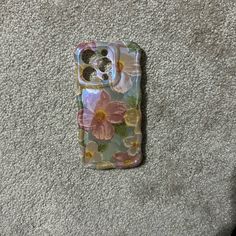 a phone case with flowers on it laying on the ground