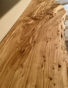 the edge of a wooden table with white walls in the background and wood grains on it