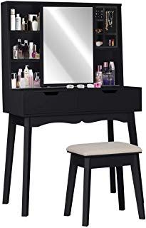 a black vanity and stool with a mirror on it's side, next to a white stool