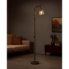 a lamp that is on top of a pole in a living room with a couch