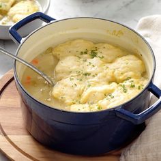 a pot filled with chicken and dumplings on top of a wooden cutting board