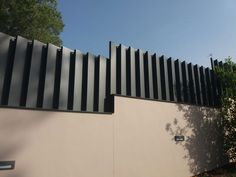 a black and white striped fence next to a building with trees in the back ground