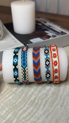 a stack of bracelets sitting on top of a table next to a white candle