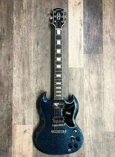 a blue electric guitar sitting on top of a wooden floor