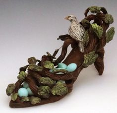 a figurine of a bird sitting on top of a branch with eggs in it