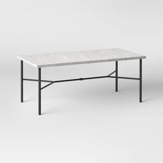 a white marble top coffee table with black metal frame legs on an isolated grey background