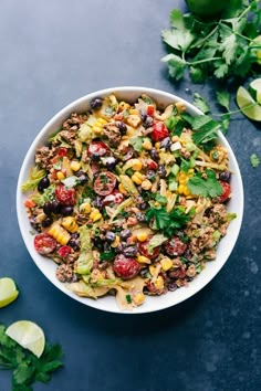 a white bowl filled with corn, black beans and cilantro on top of a blue surface