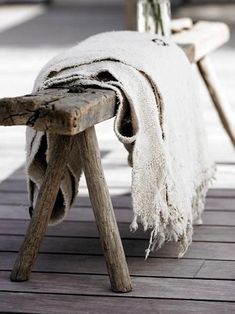 an old wooden bench with a blanket on it