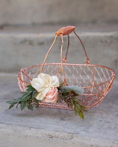 a pink wire basket with flowers in it sitting on the ground next to some steps