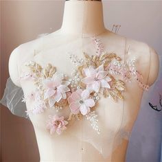 the back of a mannequin's dress with flowers and pearls on it