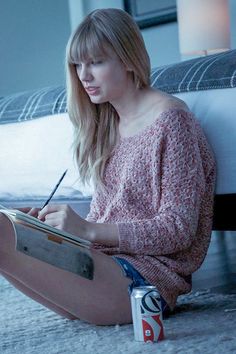 a woman sitting on the floor with a book and pen in her hand while writing