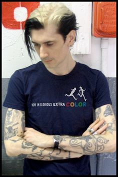 a man with tattoos on his arms standing in front of a wall