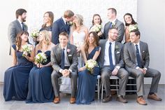 a group of people sitting next to each other in front of a white wall wearing suits and ties