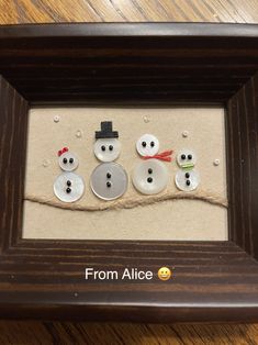 three snowmen in a frame with buttons attached to them