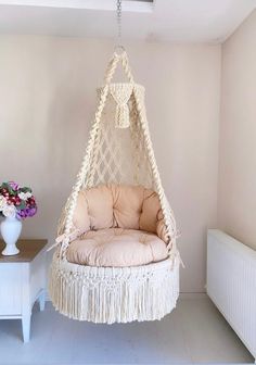 a hammock chair hanging from the ceiling in a room with white walls and flooring