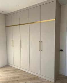 an empty room with white cupboards and wood flooring in the middle of it