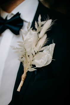 a man in a tuxedo and bow tie with feathers on his lapel