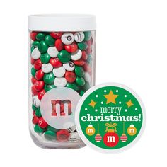 a glass jar filled with lots of christmas candies next to a round sticker