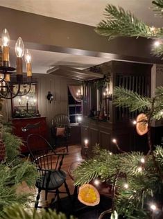 a christmas tree in the corner of a living room with lights on and decorations hanging from it