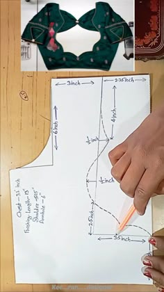 a woman's hand holding a pencil next to a piece of paper with sewing diagrams on it