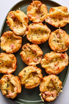 mini pizzas with cheese and herbs are on a green plate, ready to be eaten