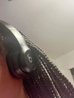 a close up of a person wearing headphones with braids on their hair and looking at the camera