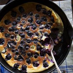 a skillet filled with blueberries and other toppings next to a spoon on a table