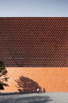 two people are standing in front of a red brick building with an intricate design on the side