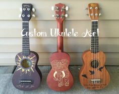 three ukulele guitars are lined up against a wall with the words custom ukulele art written on them