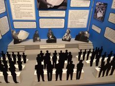 there are many figurines on display in this museum case with information about the people