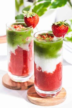 two desserts with strawberries on the top and green liquid in the middle, sitting next to each other