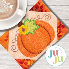 a cup of coffee sitting on top of a table next to a napkin with a pumpkin design