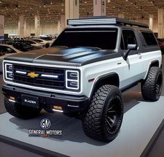 a white truck is on display in a showroom with other cars and people looking at it