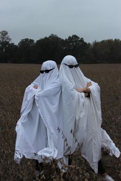 two people dressed in white walking through a field