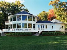 a large white house sitting in the middle of a lush green field next to trees