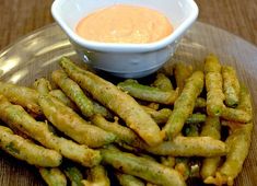 a plate full of fried green beans with dipping sauce