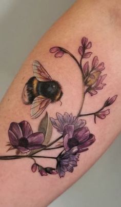 a tattoo with a bee and flowers on it