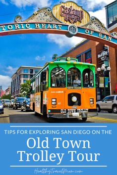 an orange bus driving down a street next to a tall sign that says old town trolley tour