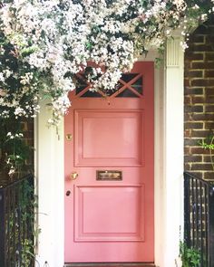 a pink door with white flowers growing over it