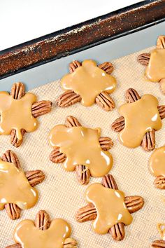 the cookies are covered in caramel icing and have pecans arranged on them