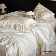 there is a white bed with ruffles and pillows on the bottom half of it