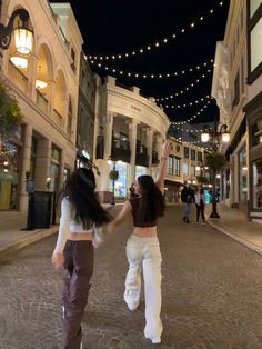 two women walking down a street holding hands