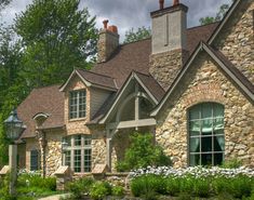 a stone house with lots of windows and landscaping