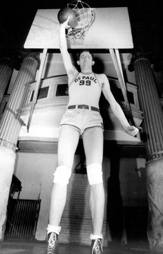 a man holding a basketball up to the air with his hands in the air while wearing shorts and sneakers