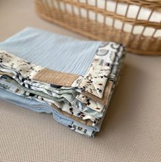 three folded cloths sitting on top of each other next to a wicker basket