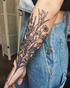 a woman's arm with flowers and leaves tattooed on the left side of her arm