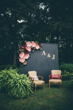 two chairs sitting next to each other in front of a sign with flowers on it