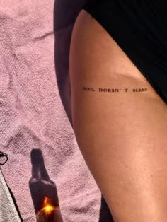 a woman's thigh with a beer bottle and the words devil doesn't sleep written on it